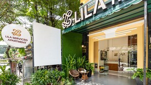 A Lila serviced apartment entrance with a green awning, a reception desk, and potted plants. - LILA Hotel & Apartments (Ho Chi Minh City)