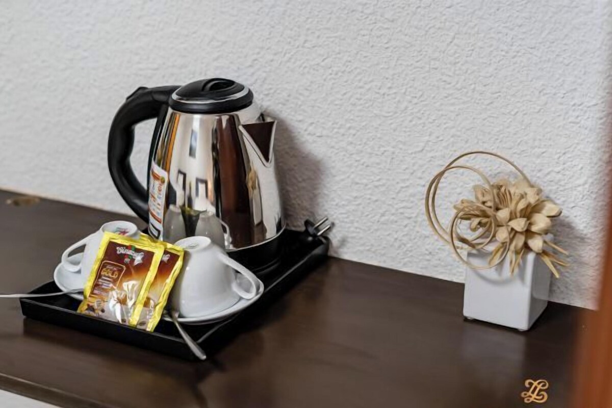 Eine Kaffeemaschine, Tassen und ein Kaffeepäckchen auf einem Tablett auf einem Holztisch.