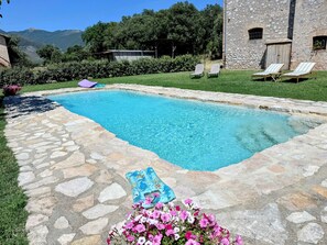 A rectangular swimming pool with stone tiles, surrounded by a stone deck and a grassy area. - Elegant Farmhouse Retreat in Poreta, Italy (Poreta)