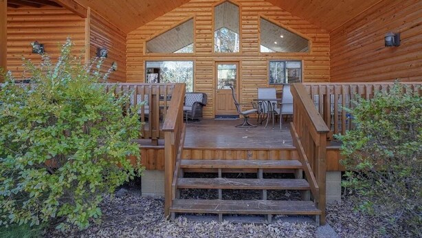 Una baita di legno con veranda, gradini e vista sulla foresta circostante.
