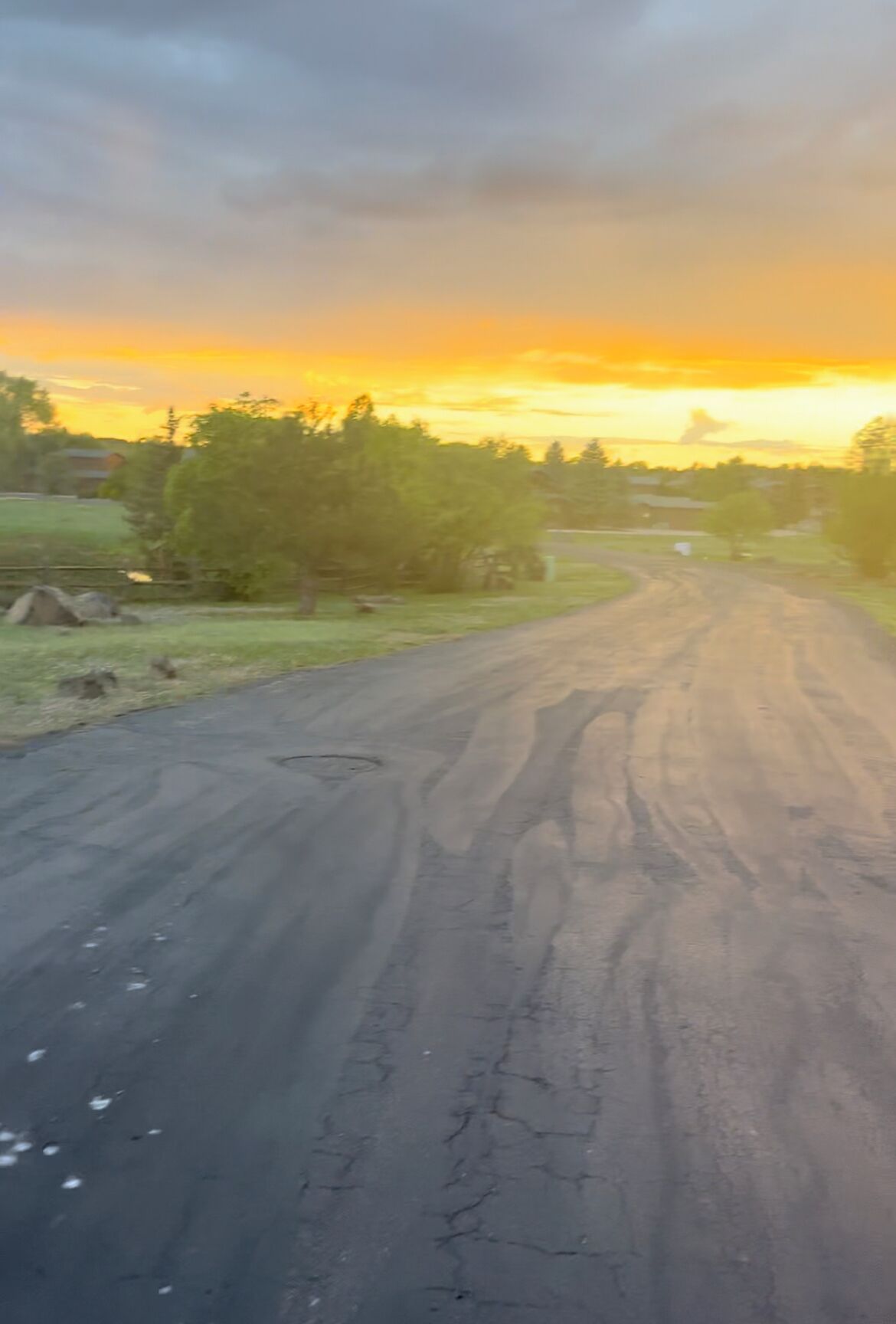A rural road with a sunset in the background.