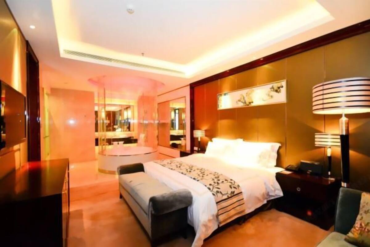 Ein modernes Hotelzimmer mit einem großen Bett, Nachttischen, einem Schreibtisch und einem Spiegel.