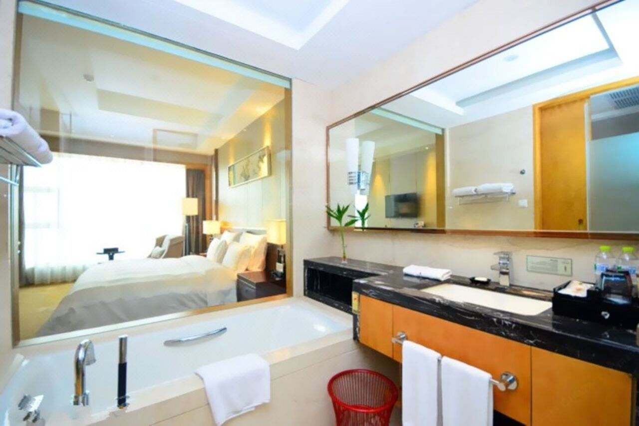 A modern bathroom with a large mirror, a bathtub, a sink, and a red basket.
