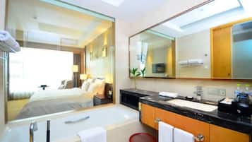 A modern bathroom with a large mirror, a bathtub, a sink, and a red basket.