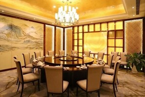 Una mesa redonda de comedor con sillas, una araña y decoración tradicional.