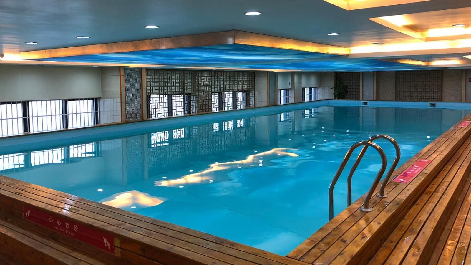 Una piscina interior con muelle de madera y barandillas de seguridad.