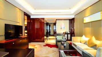 A modern hotel room with a flat-screen TV, a sofa, a coffee table, and a red carpet.