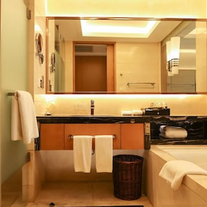 Ein modernes Badezimmer mit einem großen Spiegel, einer Badewanne und einem Waschtisch mit schwarzer Arbeitsplatte.