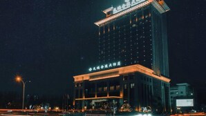 Ett högt hotell med upplyst skyltning och en framträdande entré.