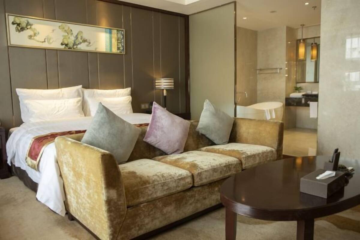 Ein Hotelzimmer mit Bett, einer Couch, einem runden Tisch und einem durchgegangenen Tür erkennbaren Badezimmer.