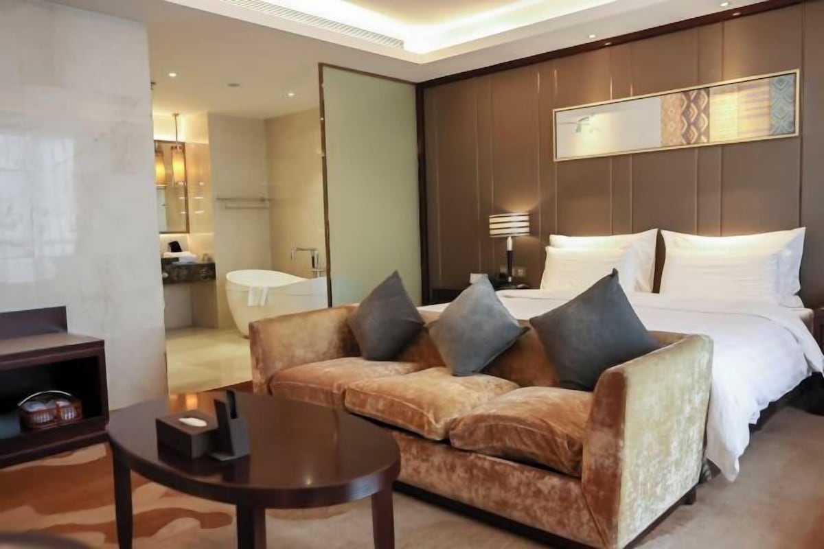 Ein Hotelzimmer mit Bett, Sofa, Tisch und Spiegel.