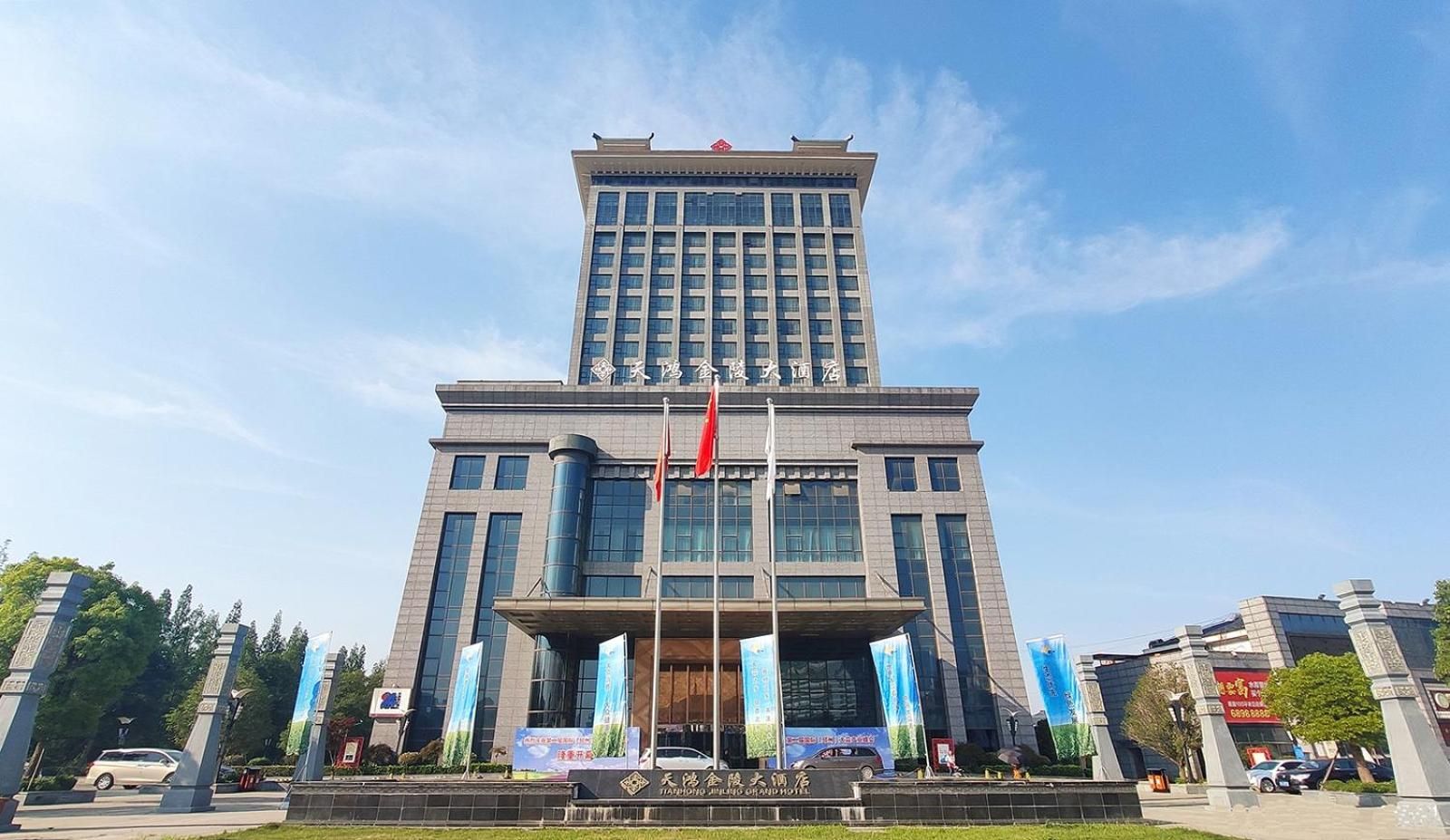 A multi-story building with a prominent entrance, flags, and banners.