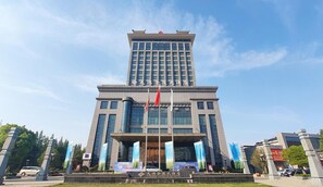 A multi-story building with a prominent entrance, flags, and banners. - Tianhong Jinling Grand Hotel (Xuzhou)