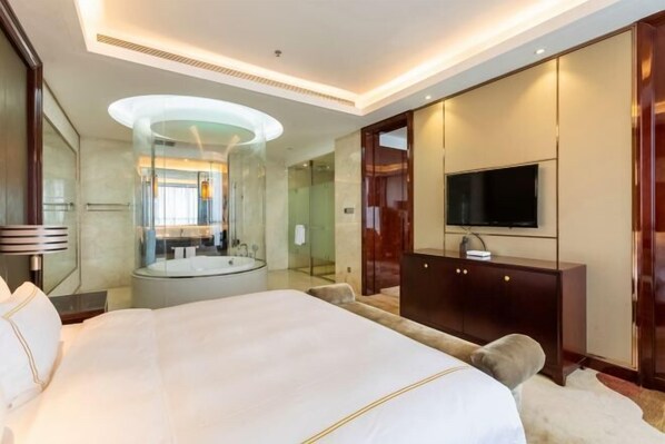 A hotel room with a large bed, a TV, a mirror, and a glass-enclosed shower. - Tianhong Jinling Grand Hotel (Xuzhou)