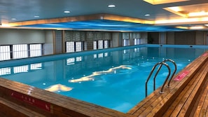 Ein Hallenbad mit Holzterrasse und Sicherheitsgeländern.