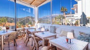 A terrace with wicker furniture, a stone wall, and a view of the hills. - Malaga Hills, Adults Only boutique, wellness & hiking Eco-Hotel (Còmpeta)