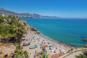 A beach with clear blue water, a rocky shoreline, and a variety of beach umbrellas. - Malaga Hills, Adults Only boutique, wellness & hiking Eco-Hotel (Còmpeta)