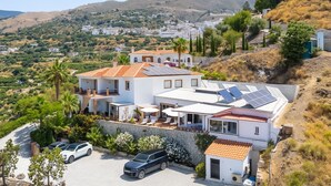 A modern villa with solar panels, a stone wall, and a view of a hillside town. - Malaga Hills, Adults Only boutique, wellness & hiking Eco-Hotel (Còmpeta)