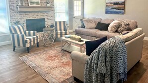 Una sala de estar acogedora con chimenea, sillones a rayas, un sofá y una mesita de centro.