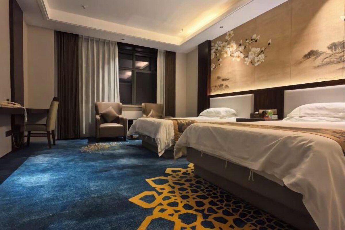 A hotel room with a large bed, a desk, and a chair.
