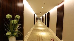Ein Hotelkorridor mit Marmorboden, Holzvertäfelung an den Wänden und einer Blumenkomposition links.