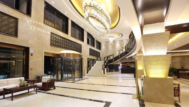 Eine geräumige Lobby mit einem beeindruckenden Chandelier, einer Treppe und einem Empfangsschalter.