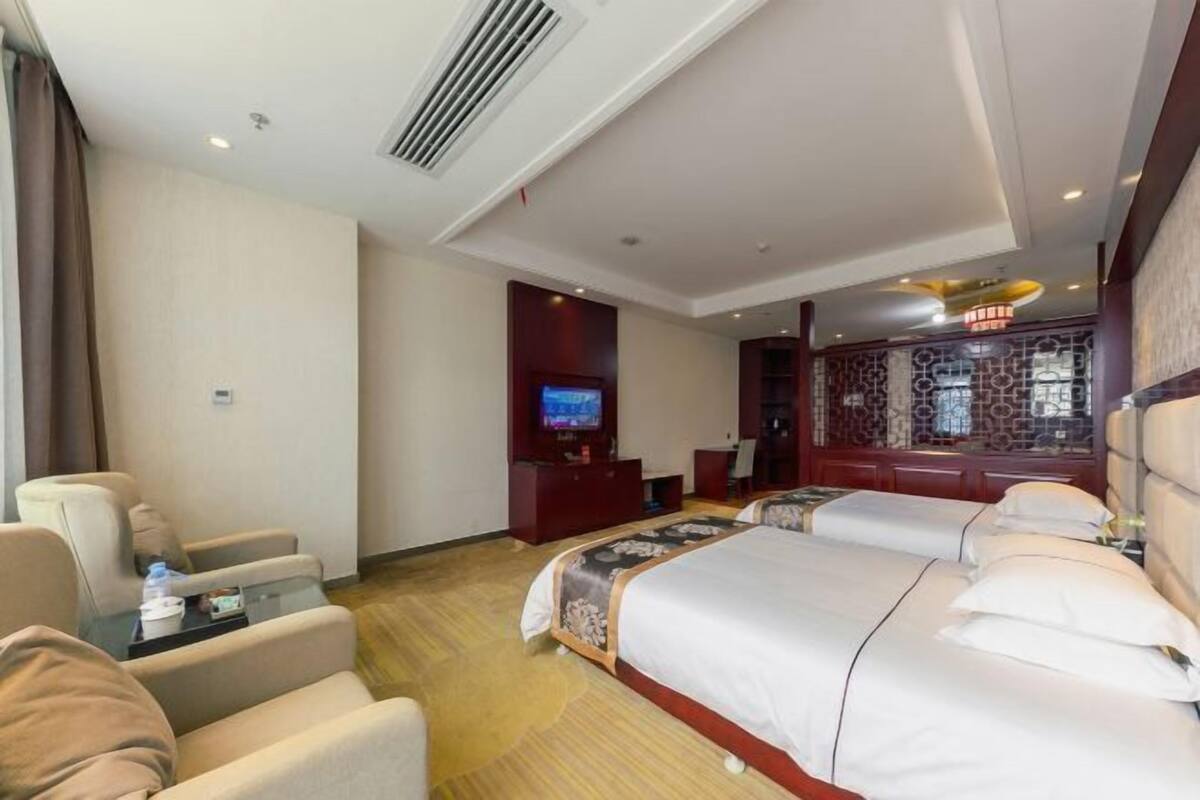 A hotel room with a large bed, two bedside tables, a TV, and a seating area with chairs.