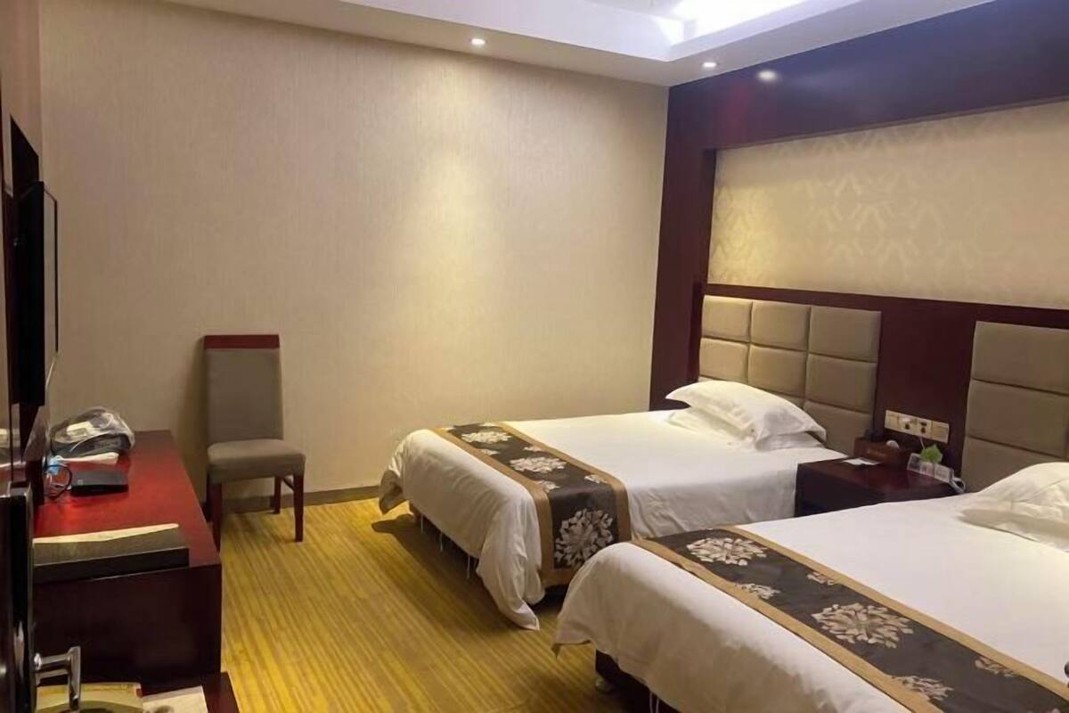A hotel room with two beds, a desk, and a chair.