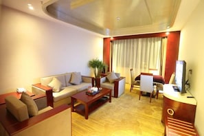 A modern hotel room with a sofa, armchairs, a coffee table, a TV, and a desk. - Red Star International Hotel (Jinggangshan City)