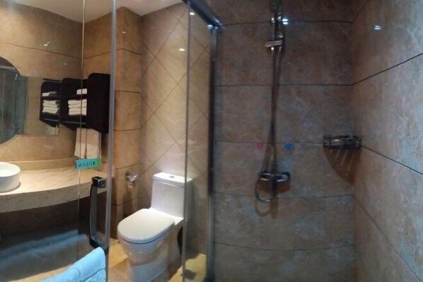 Un baño moderno con cabina de ducha de vidrio, inodoro y lavamanos.