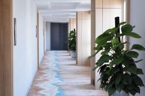 A hallway with a patterned floor, wooden walls, and potted plants. - Panda Prince Hotel (Dazhou)