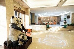 Un vestíbulo con una recepción, una estatua de panda y un piso pulido.