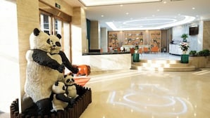 Een lobby met een receptiebalie, een groot panda-beeld en een modern plafondontwerp.