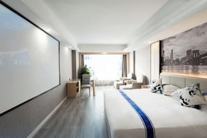 Una habitación de hotel moderna con una cama grande, un escritorio y vistas a un paisaje urbano.