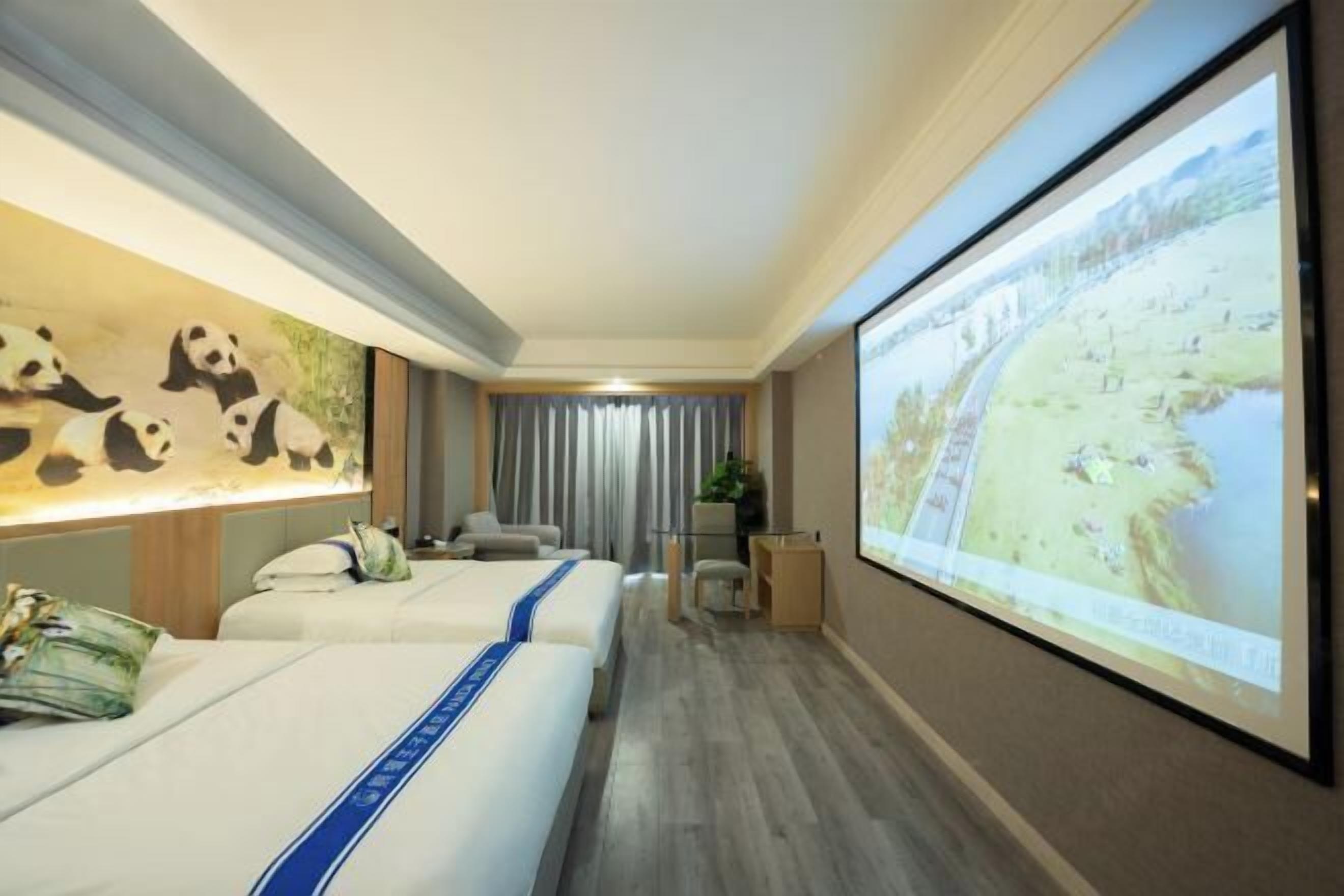 Ein Hotelzimmer mit zwei Betten, einem großen Bildschirm, der eine schöne Aussicht zeigt, und einem Wandgemälde mit einem Panda.