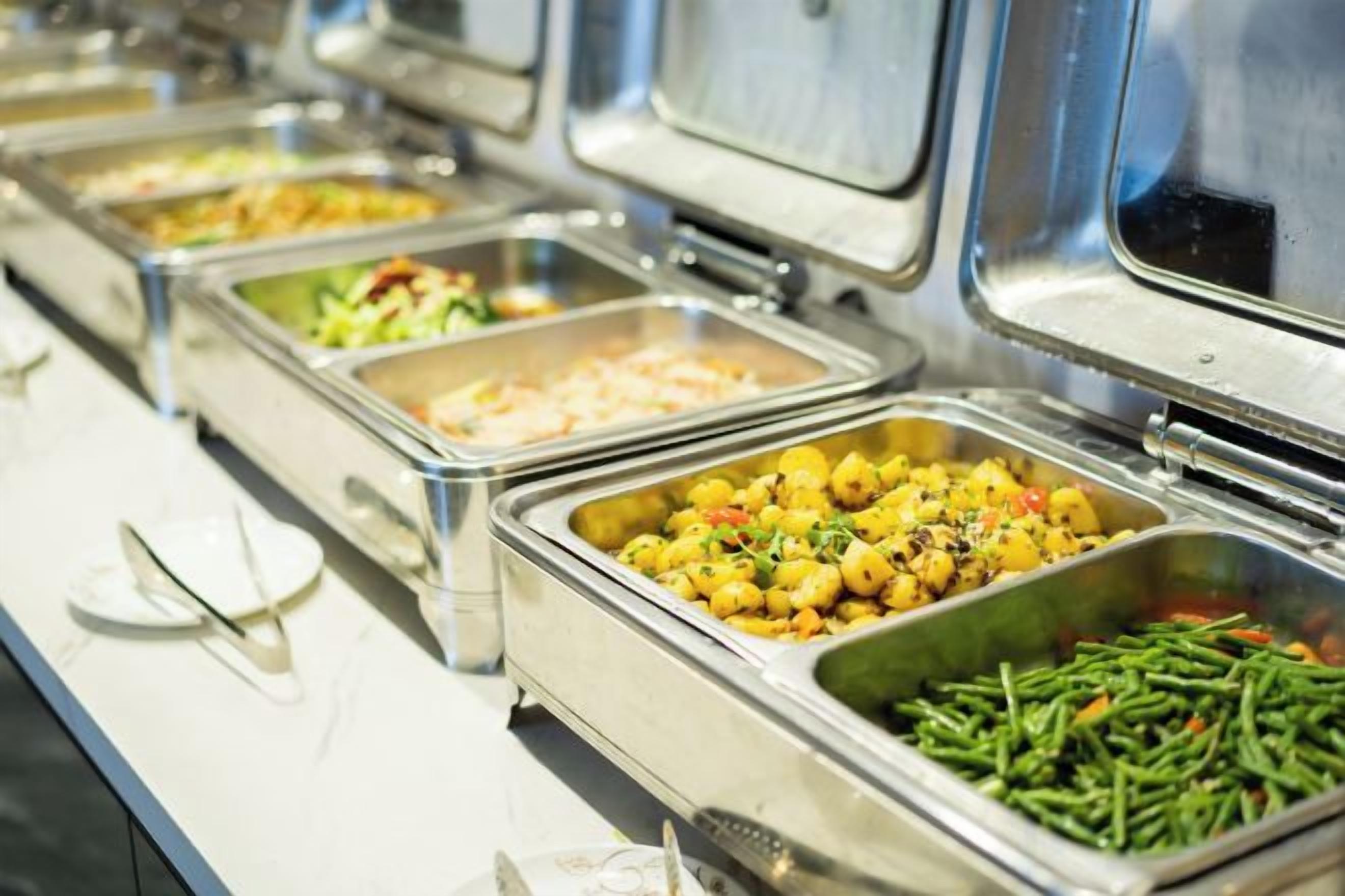 Un buffet proposant une variété de plats, notamment des salades, des pommes de terre et des haricots verts.