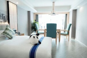 Una habitación de hotel moderna con una cama, un escritorio, una silla y un ventanal grande.