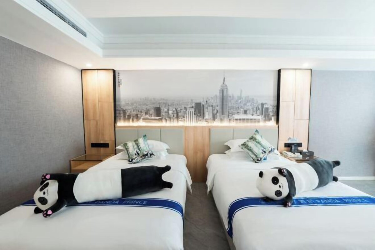 A hotel room with two beds, a cityscape mural on the wall, and a panda plush toy on each bed.