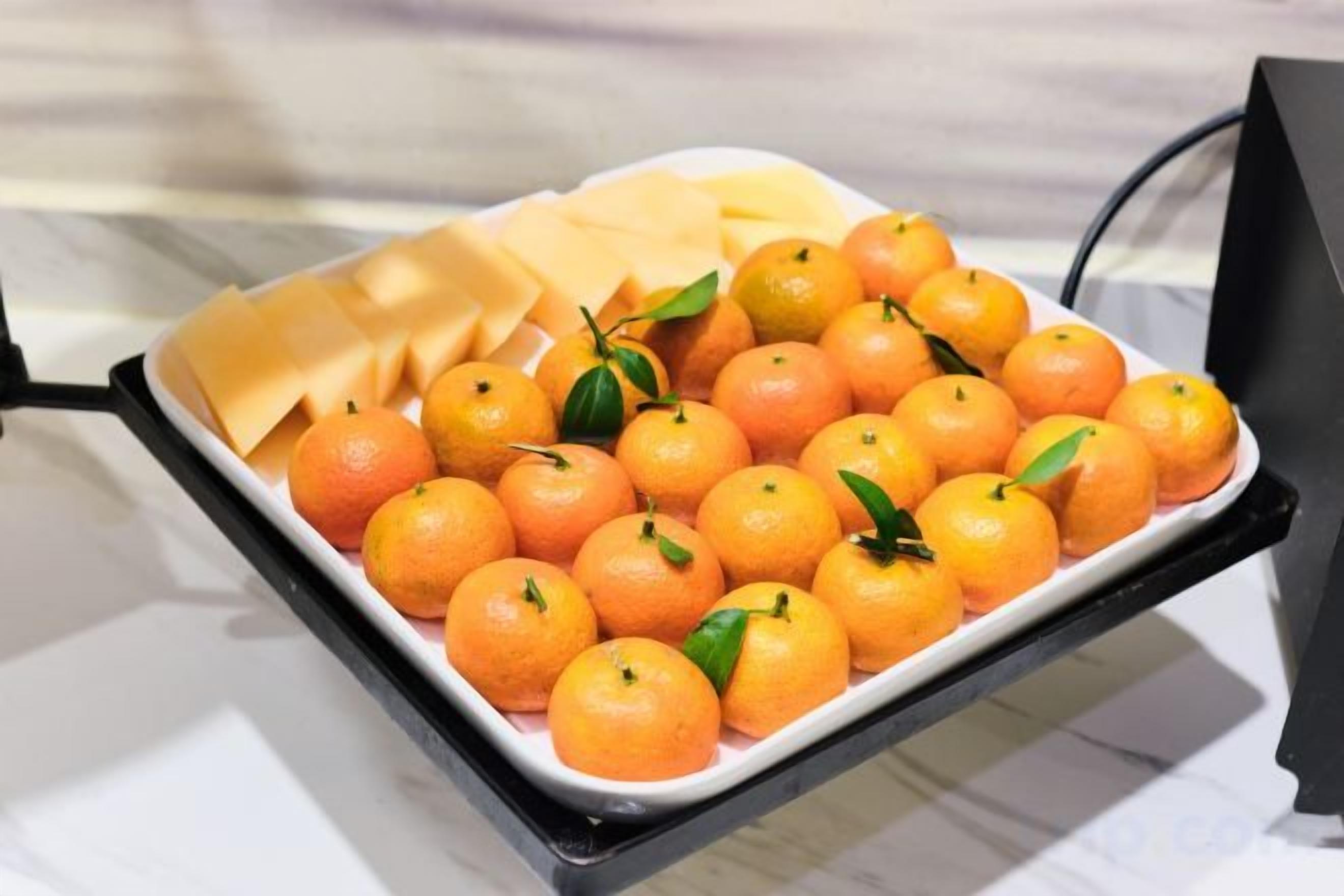 A tray with oranges and cheese on a table.