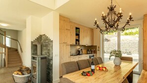 A modern kitchen with a stone fireplace, wooden cabinets, and a dining area with a table set for two.