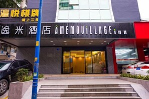 Entrada de hotel con puerta de vidrio, escalones que la conducen y un cartel sobre la puerta.