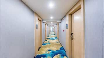 A hotel hallway with doors on both sides, a carpeted floor, and a ceiling light.