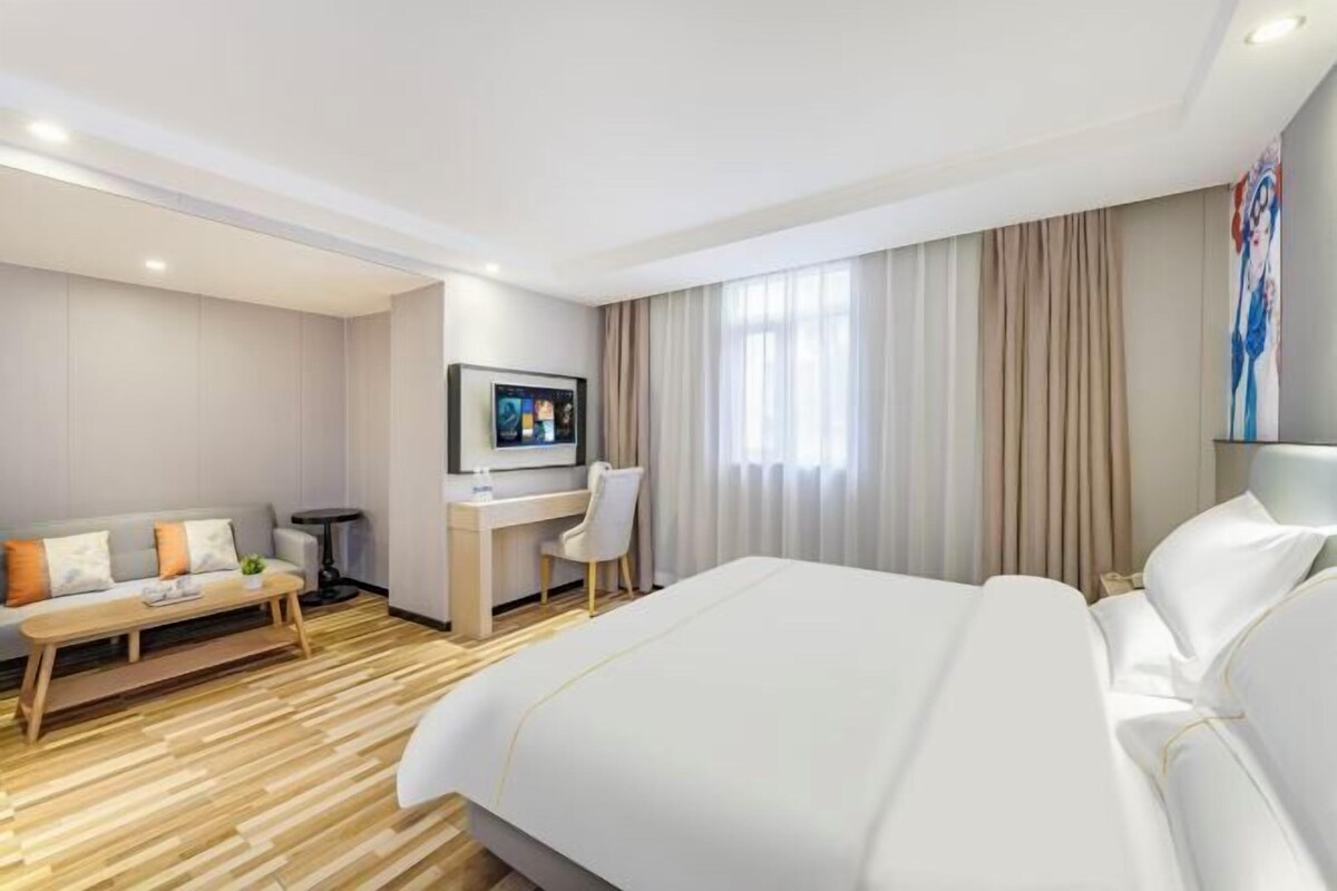 Ein Hotelzimmer mit einem großen Bett, einem Schreibtisch, einem Sessel, einem Fernseher und einer Couch.