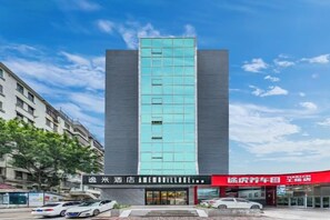 A modern hotel with a prominent vertical glass facade, a ground-level entrance, and adjacent commercial establishments. - Yimi Hotel (Guangzhou Xicun Subway Station) (Guangzhou)