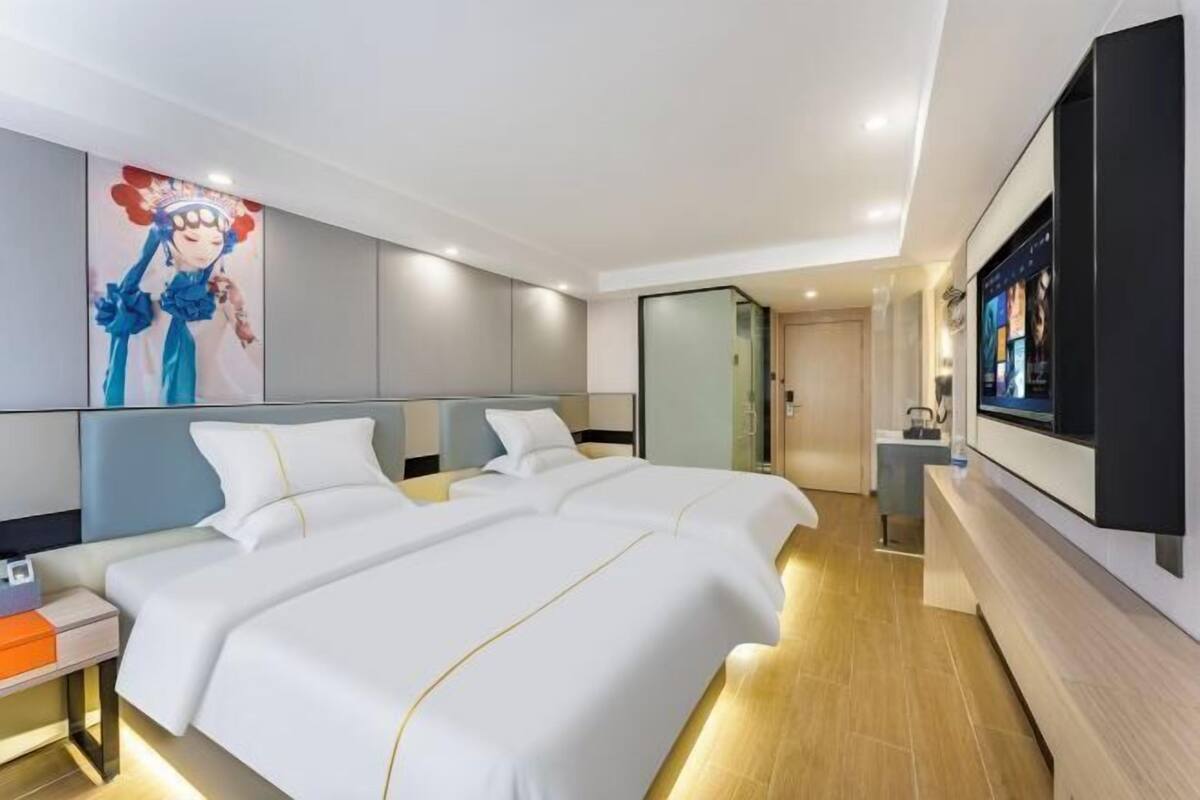 A hotel room with a large bed, a TV, and a painting on the wall.