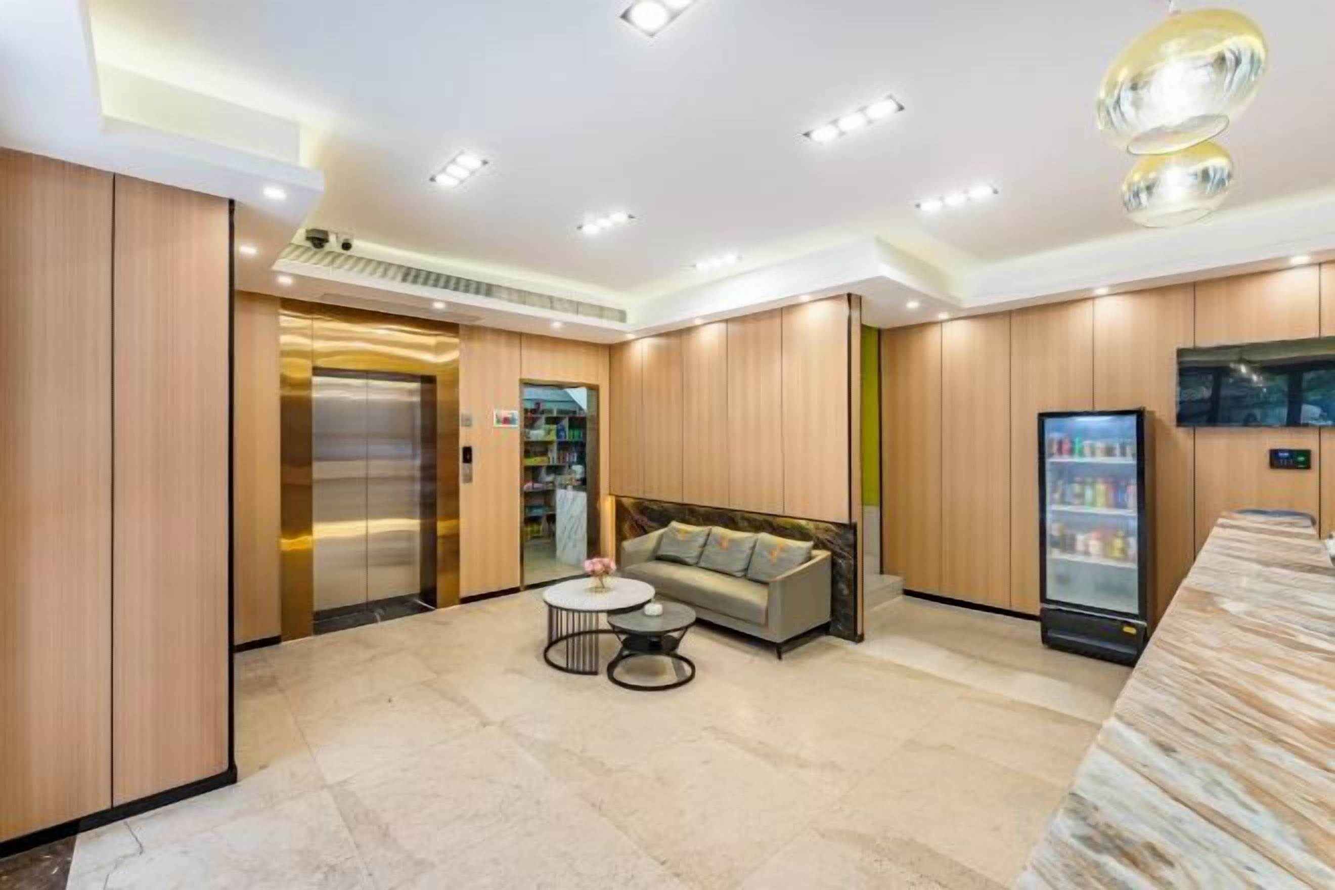 A hotel lobby with a reception desk, a sofa, a coffee table, an elevator, and a refrigerator.