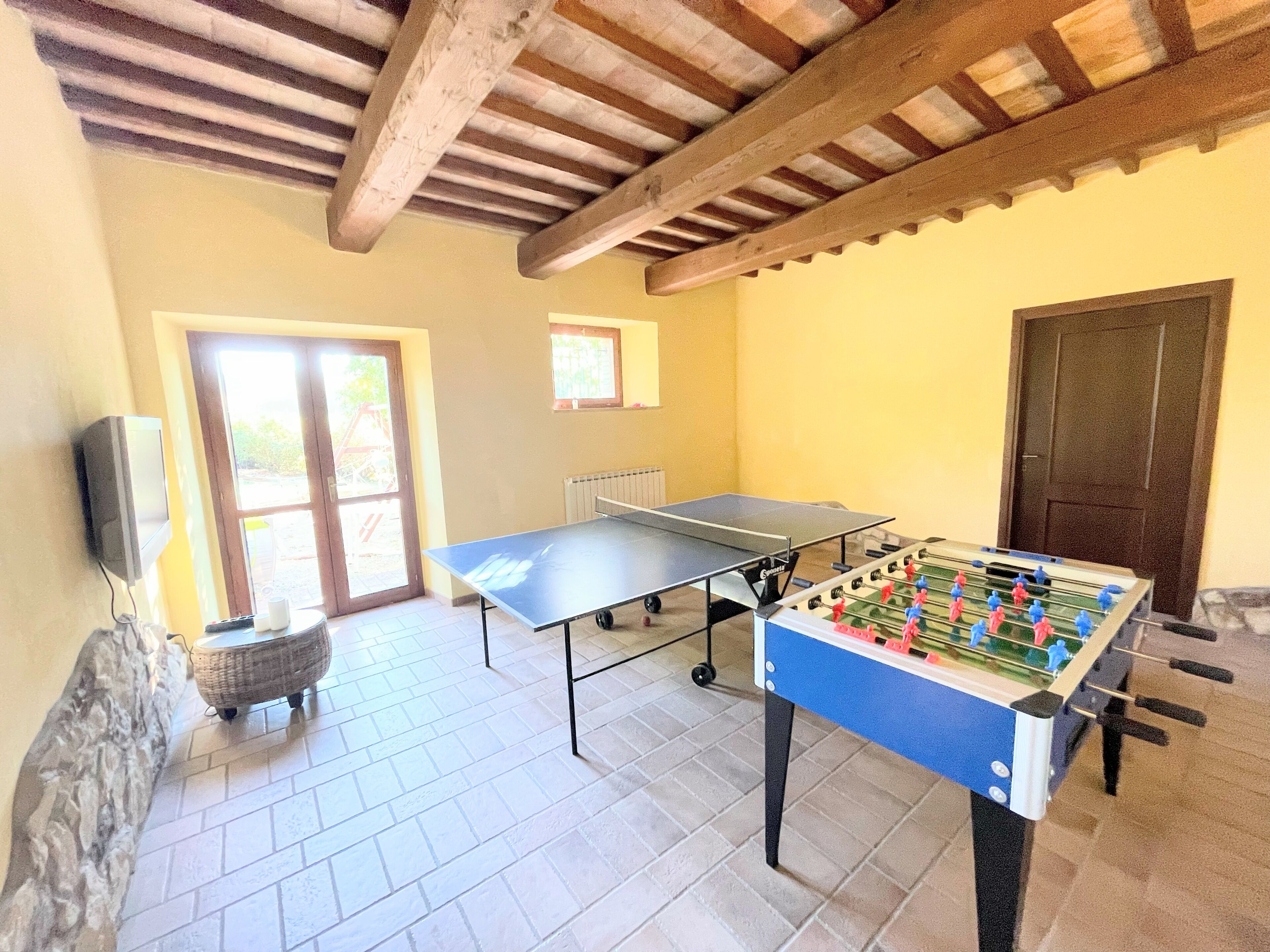 Une pièce équipée d’une table de ping-pong, d’un baby-foot et d’un téléviseur.