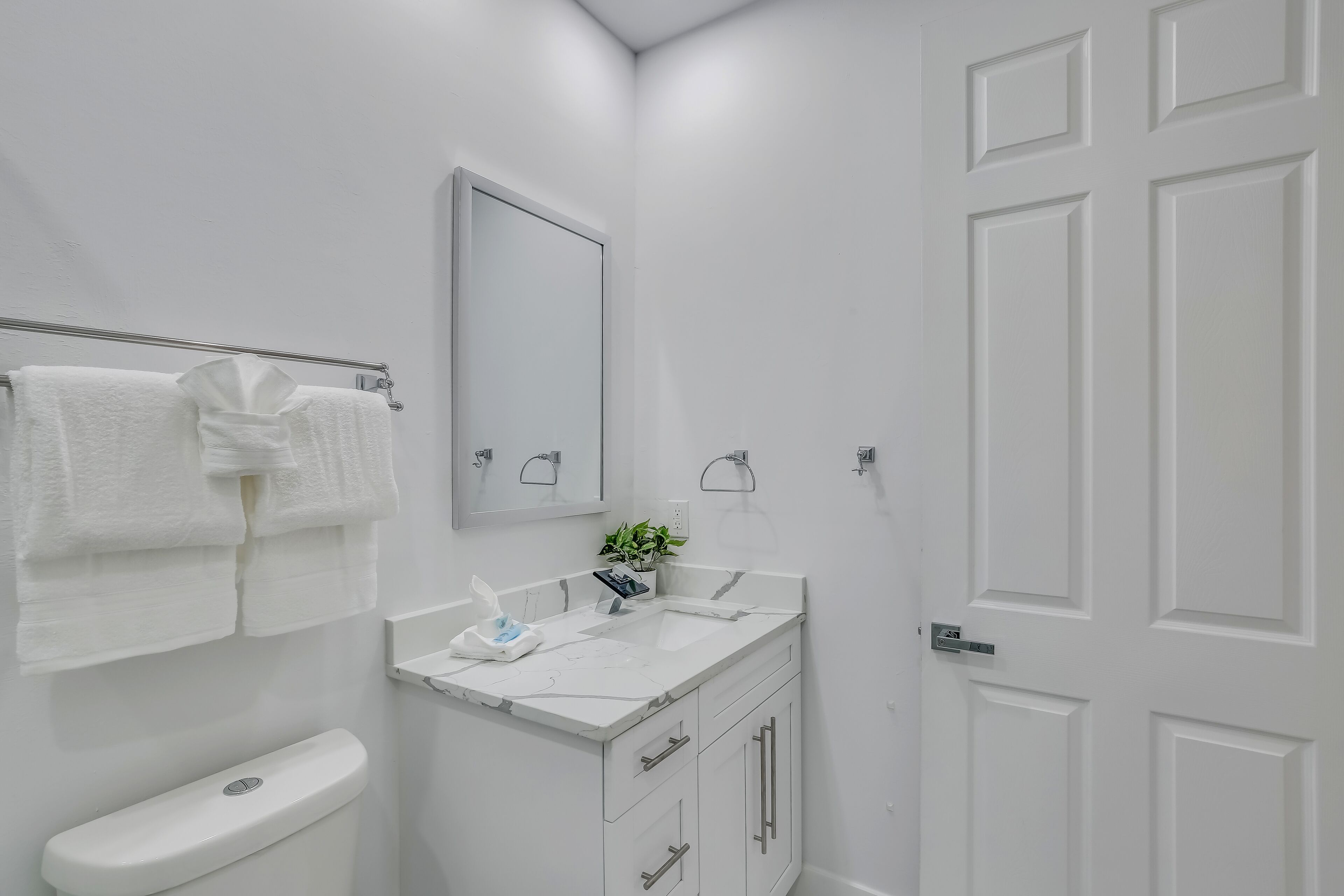 A modern bathroom with a white vanity, a toilet, and a large mirror.
