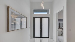 Ein moderner Flur mit einem großen gerahmten Kunstwerk, einer Doppeltür und einer Deckenleuchte.
