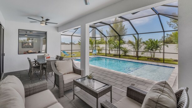 Ein moderner Außenbereich mit Pool, Korbmöbeln und Deckenventilatoren.